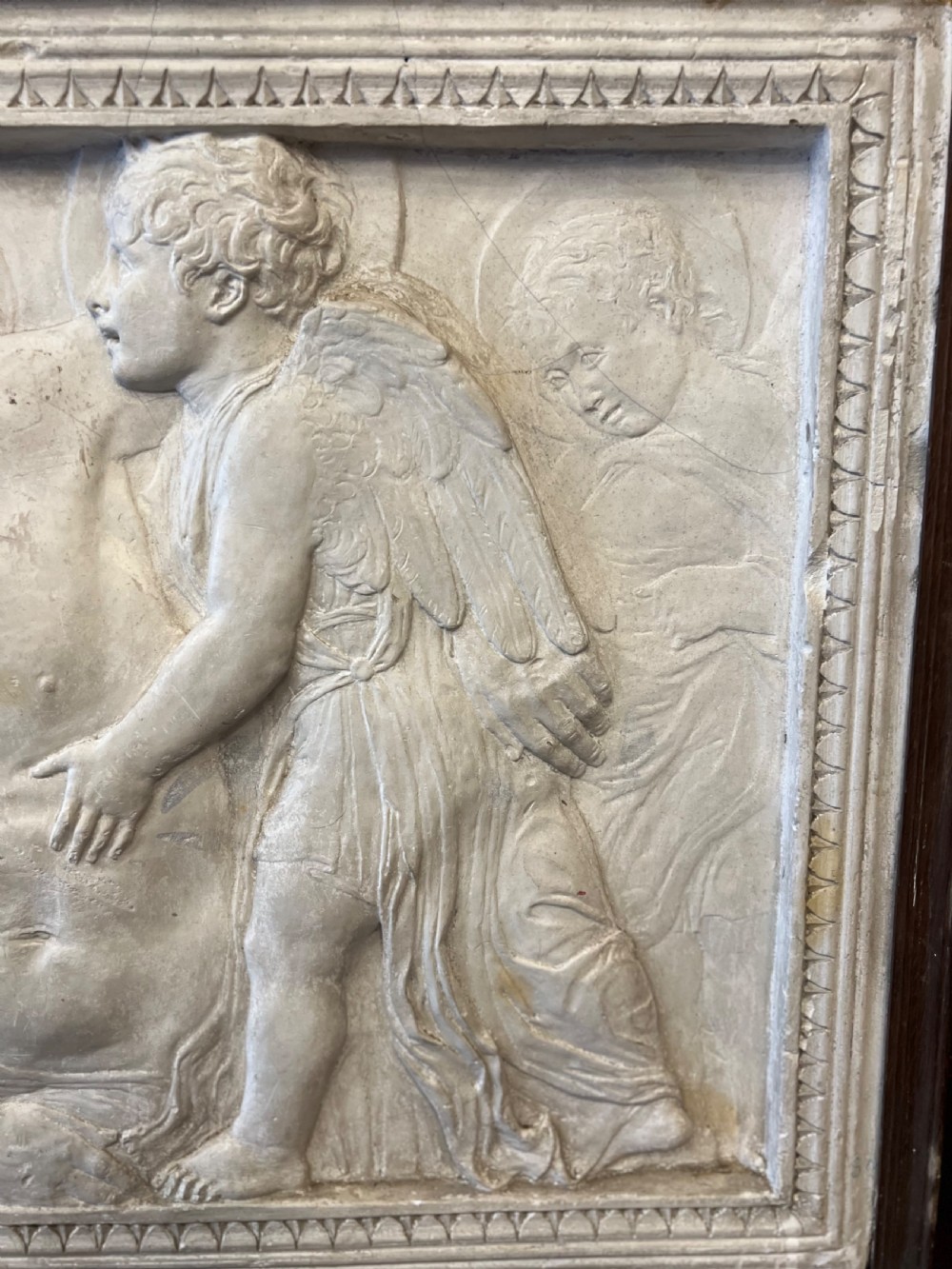 An off-white 19th-century plaster bas-relief panel depicting Christ supported by angels, framed within an inner egg-and-dart moulding and dark timber outer frame. View V