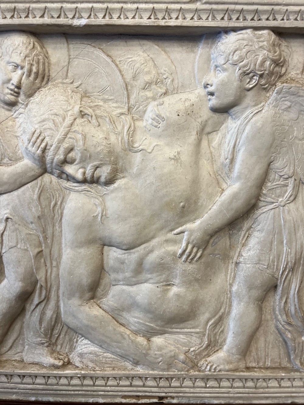 An off-white 19th-century plaster bas-relief panel depicting Christ supported by angels, framed within an inner egg-and-dart moulding and dark timber outer frame. View VII
