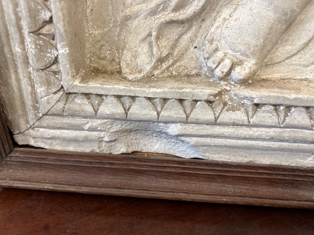 An off-white 19th-century plaster bas-relief panel depicting Christ supported by angels, framed within an inner egg-and-dart moulding and dark timber outer frame. View IX