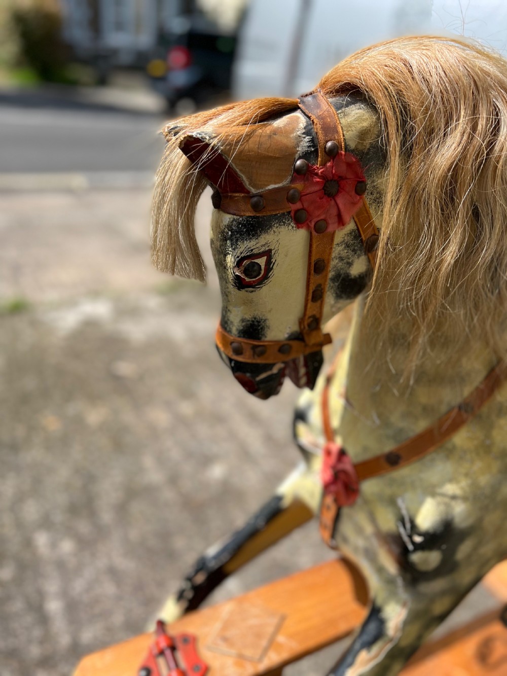 A vintage carved wooden Collinson rocking horse featuring a dapple grey painted finish, natural horsehair mane, red corduroy saddle, and leather tack on a wooden safety stand. View IV