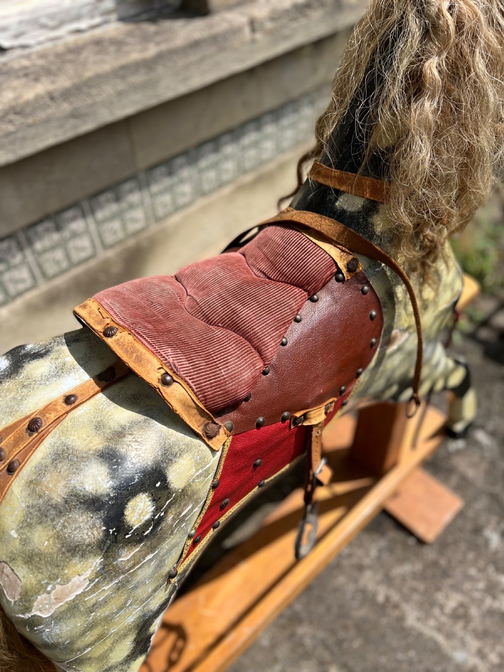 A vintage carved wooden Collinson rocking horse featuring a dapple grey painted finish, natural horsehair mane, red corduroy saddle, and leather tack on a wooden safety stand. View V