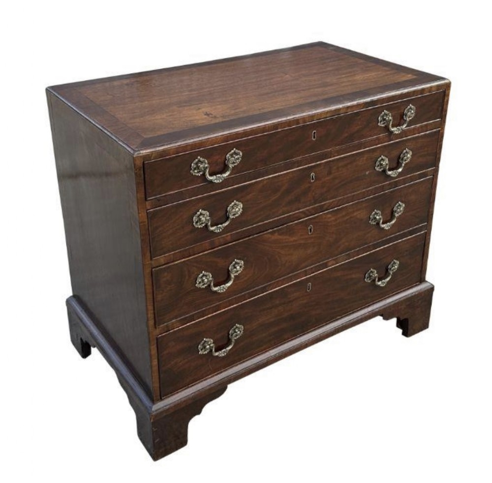A George III mahogany small chest of drawers featuring four graduated drawers with brass handles and raised on bracket feet.