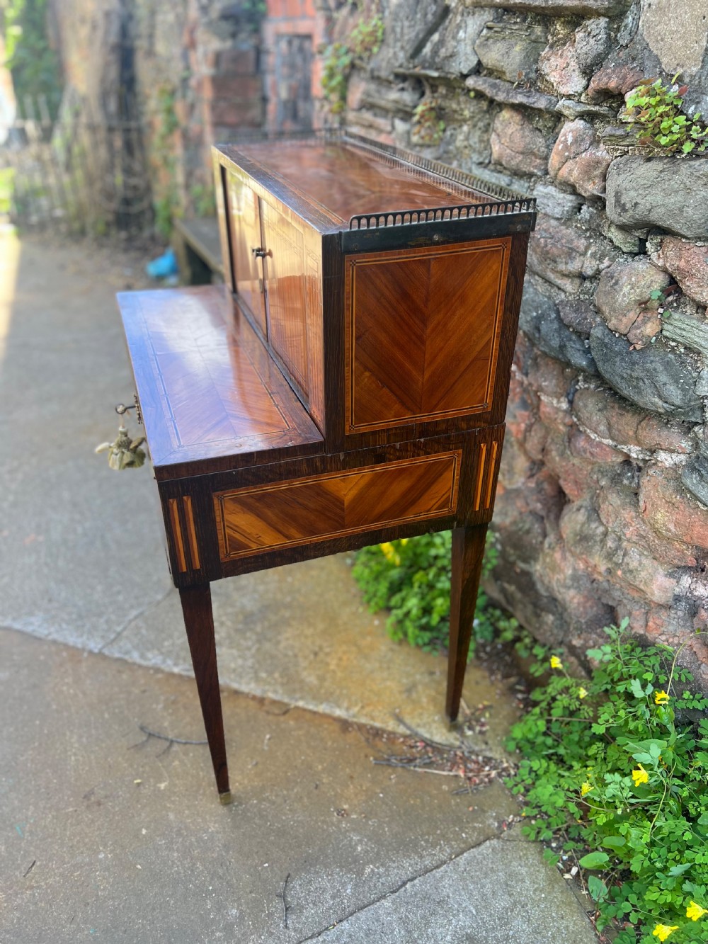 An 18th-century French bonheur de jour desk in warm brown inlaid wood, featuring square tapered legs, a single drawer with a tassel key, and a top cabinet with a pierced brass gallery. View II