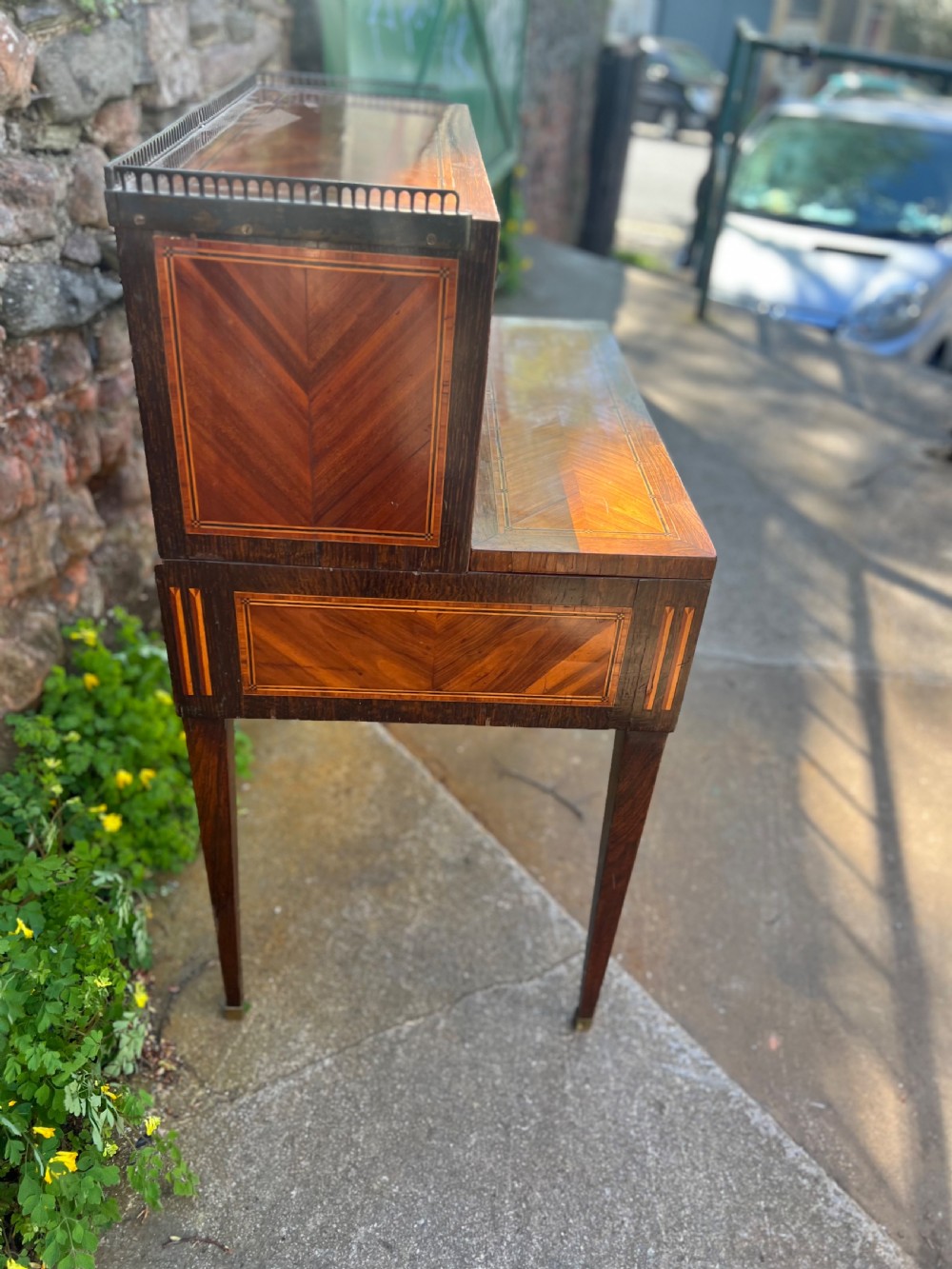 An 18th-century French bonheur de jour desk in warm brown inlaid wood, featuring square tapered legs, a single drawer with a tassel key, and a top cabinet with a pierced brass gallery. View V