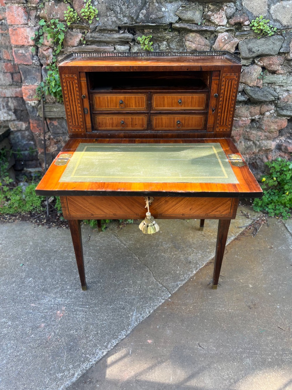 An 18th-century French bonheur de jour desk in warm brown inlaid wood, featuring square tapered legs, a single drawer with a tassel key, and a top cabinet with a pierced brass gallery. View VII