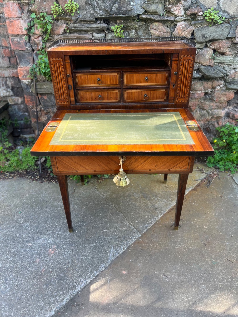 An 18th-century French bonheur de jour desk in warm brown inlaid wood, featuring square tapered legs, a single drawer with a tassel key, and a top cabinet with a pierced brass gallery. View VIII