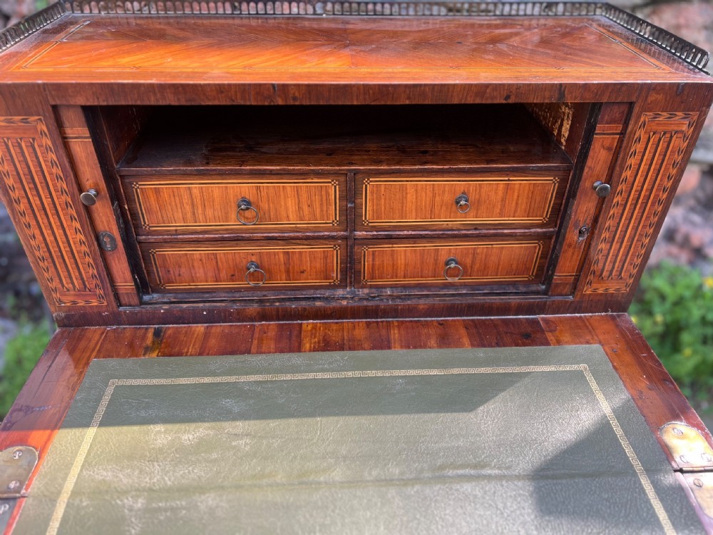 An 18th-century French bonheur de jour desk in warm brown inlaid wood, featuring square tapered legs, a single drawer with a tassel key, and a top cabinet with a pierced brass gallery. View IX