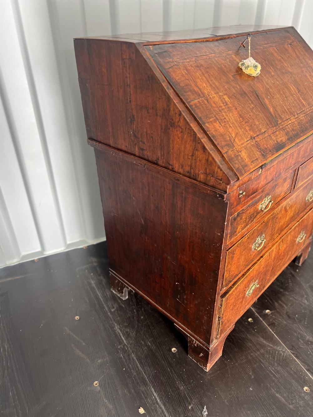 An early eighteenth-century walnut slant-front bureau featuring graduated drawers, brass drop handles, and bracket feet. View II