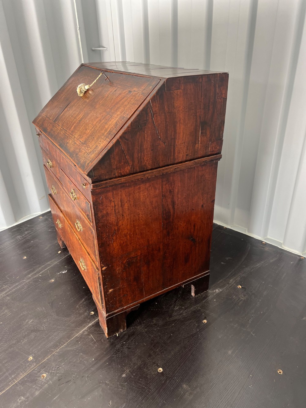An early eighteenth-century walnut slant-front bureau featuring graduated drawers, brass drop handles, and bracket feet. View III