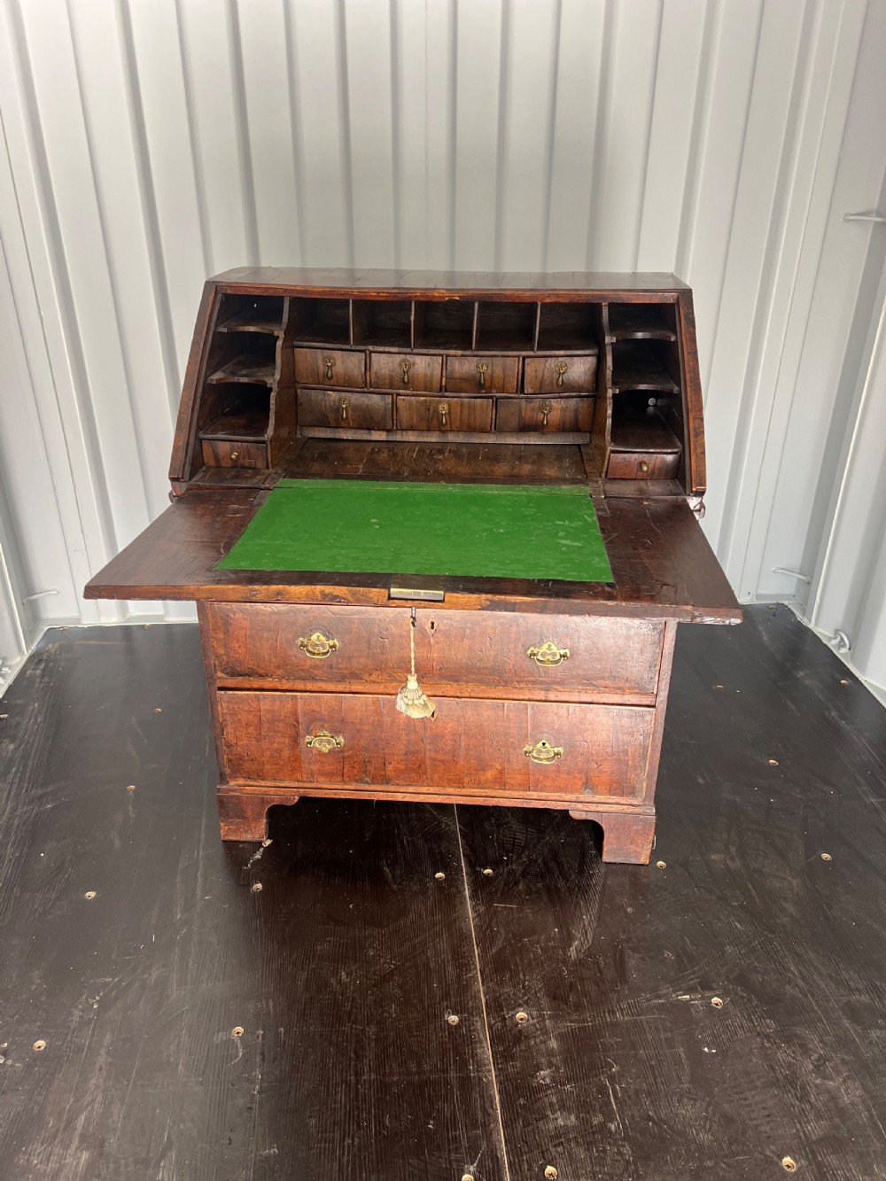 An early eighteenth-century walnut slant-front bureau featuring graduated drawers, brass drop handles, and bracket feet. View VII