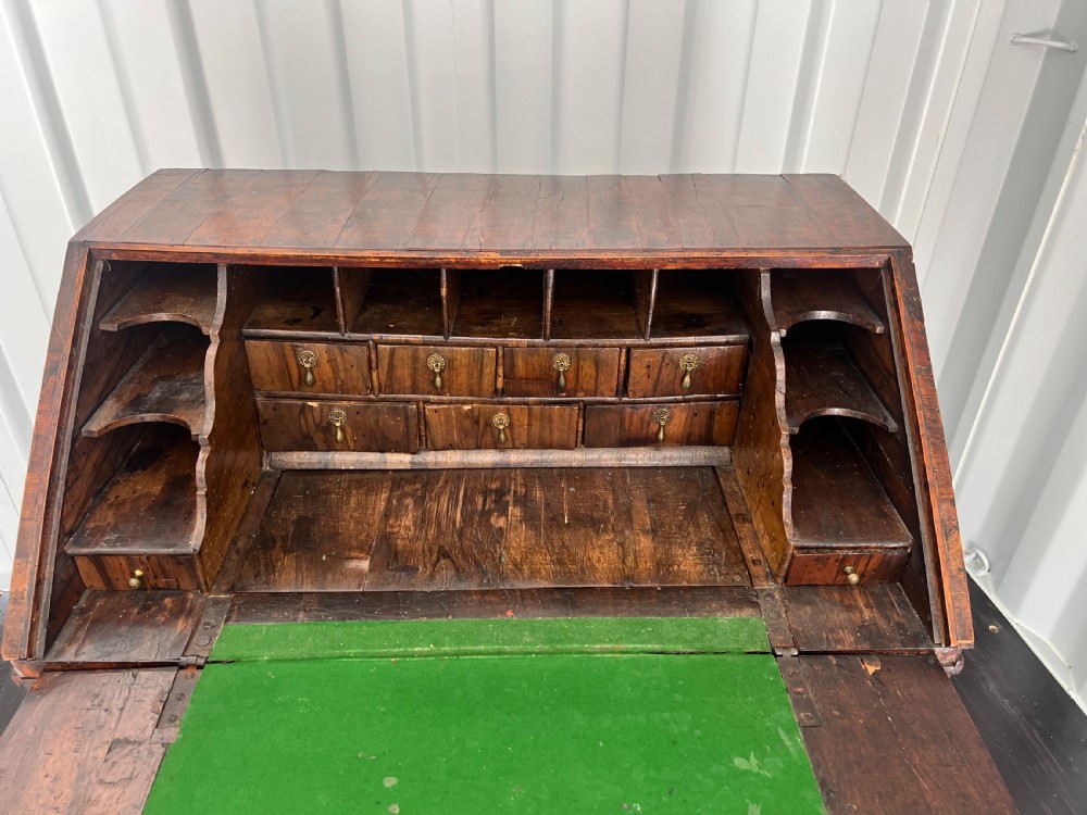 An early eighteenth-century walnut slant-front bureau featuring graduated drawers, brass drop handles, and bracket feet. View VIII