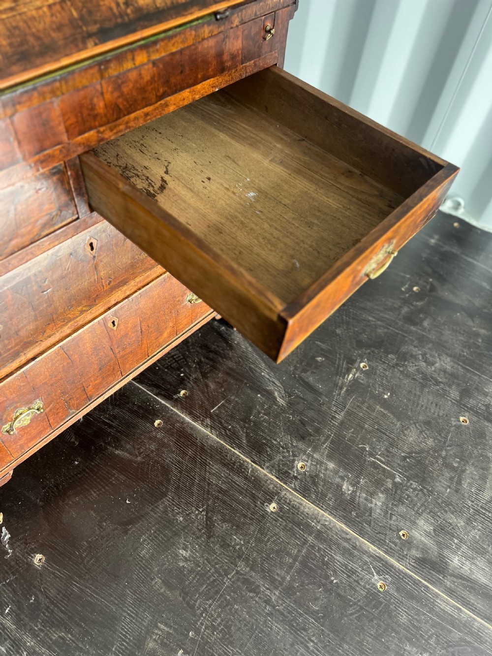 An early eighteenth-century walnut slant-front bureau featuring graduated drawers, brass drop handles, and bracket feet. View IX