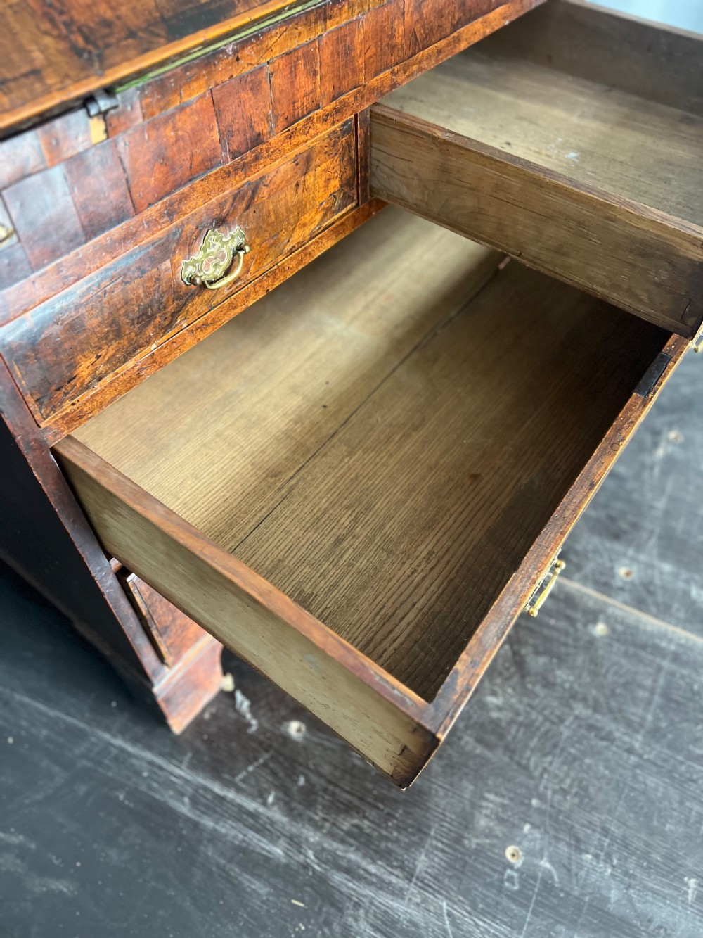 An early eighteenth-century walnut slant-front bureau featuring graduated drawers, brass drop handles, and bracket feet. View X