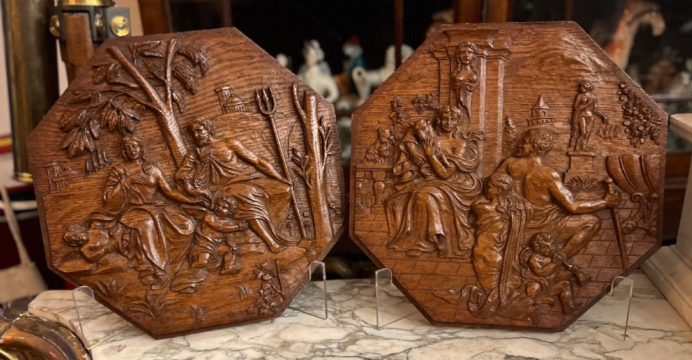 A pair of octagonal 18th-century carved oak relief plaques featuring classical mythological figures.