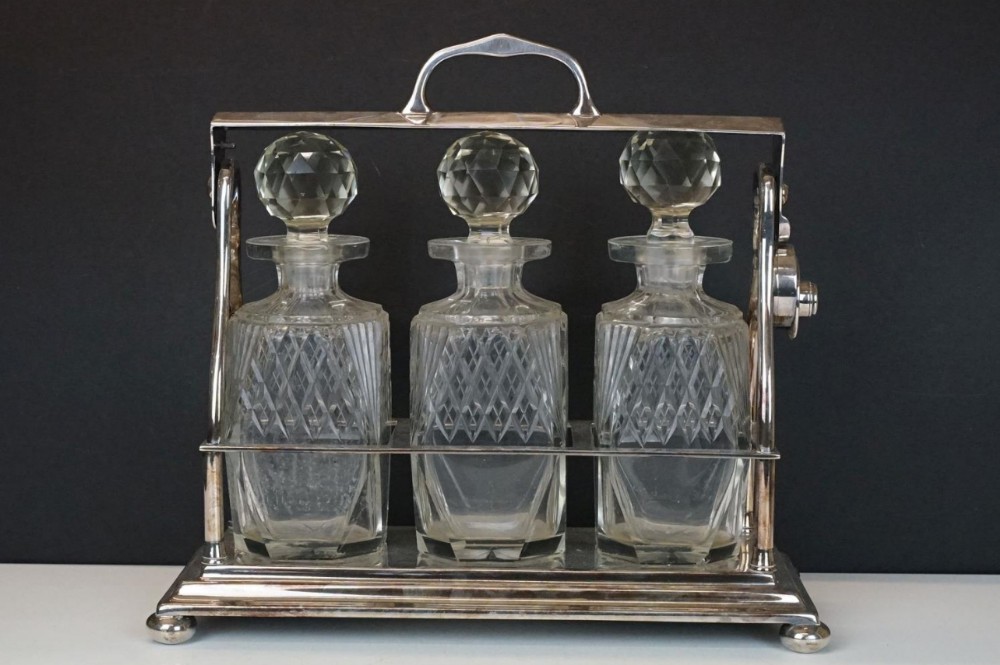 Early C20th silver plated tantalus with three bottles 