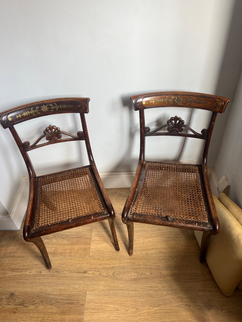A pair of Regency faux rosewood side chairs featuring brass inlaid crest rails, carved anthemion splats, sabre legs, and pale yellow upholstered seats. View III