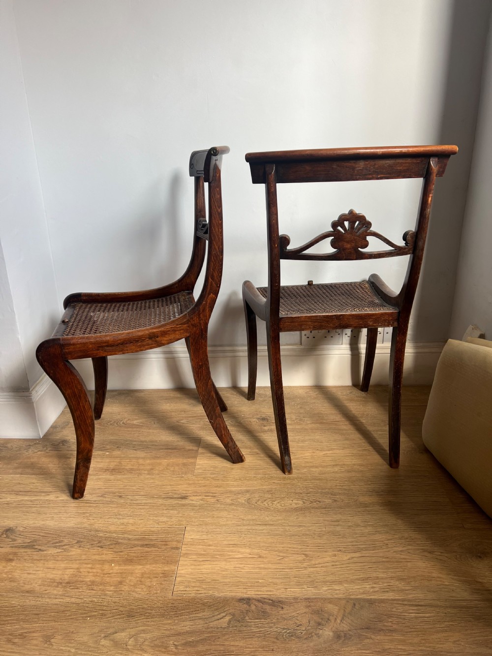 A pair of Regency faux rosewood side chairs featuring brass inlaid crest rails, carved anthemion splats, sabre legs, and pale yellow upholstered seats. View VII