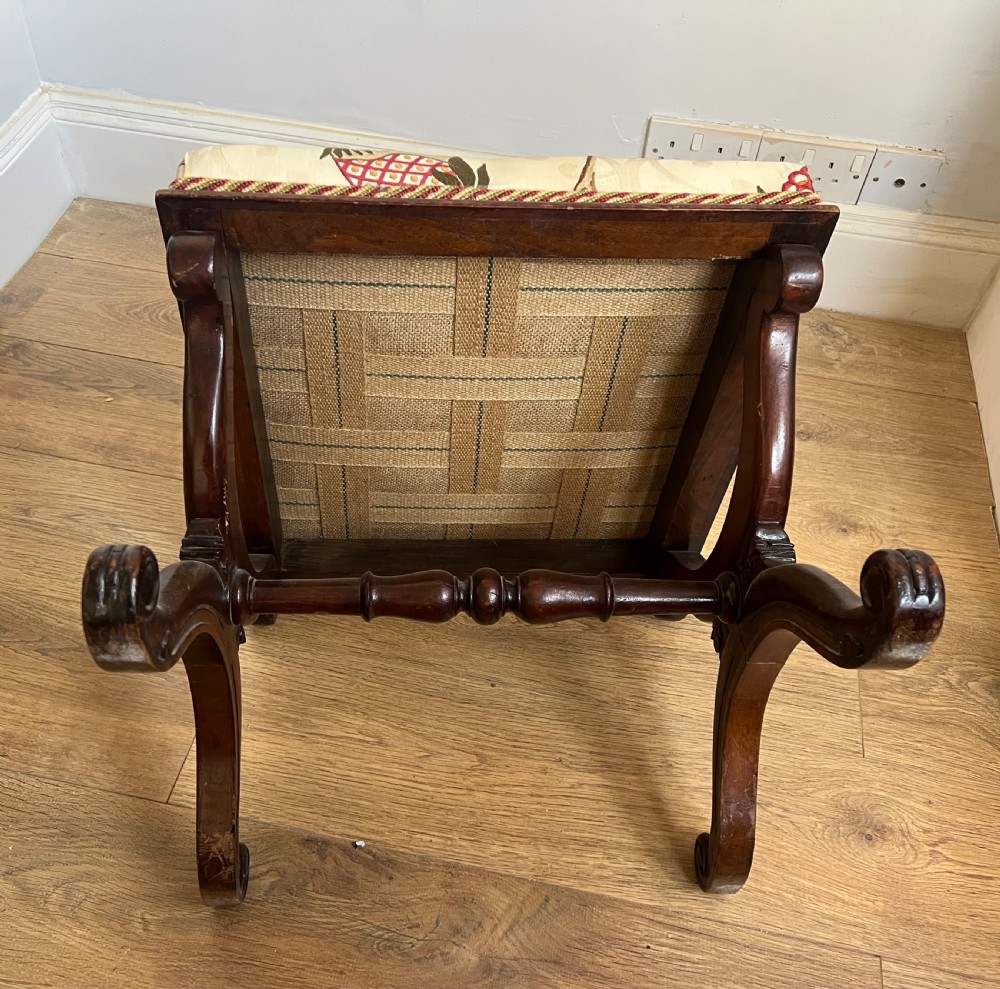 A 19th-century mahogany X-frame stool featuring carved scroll legs, a turned central stretcher, and a cream floral embroidered upholstered cushion. View III