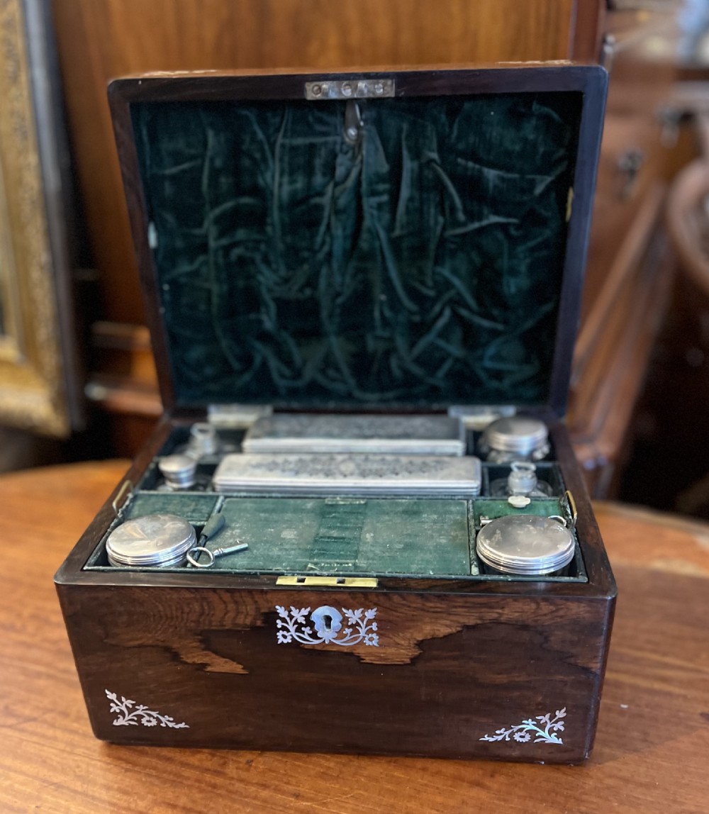 An open Victorian rosewood workbox featuring floral mother of pearl inlay, fitted green velvet interior, silver-toned vanity jars, glass bottles, and two small keys. View II