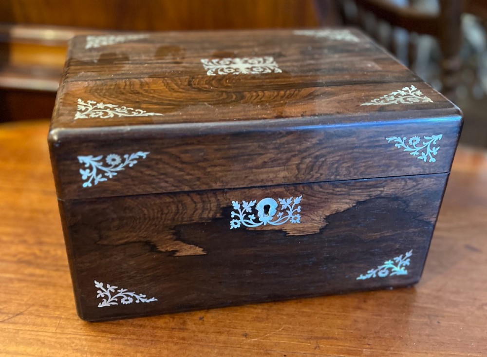 An open Victorian rosewood workbox featuring floral mother of pearl inlay, fitted green velvet interior, silver-toned vanity jars, glass bottles, and two small keys. View V