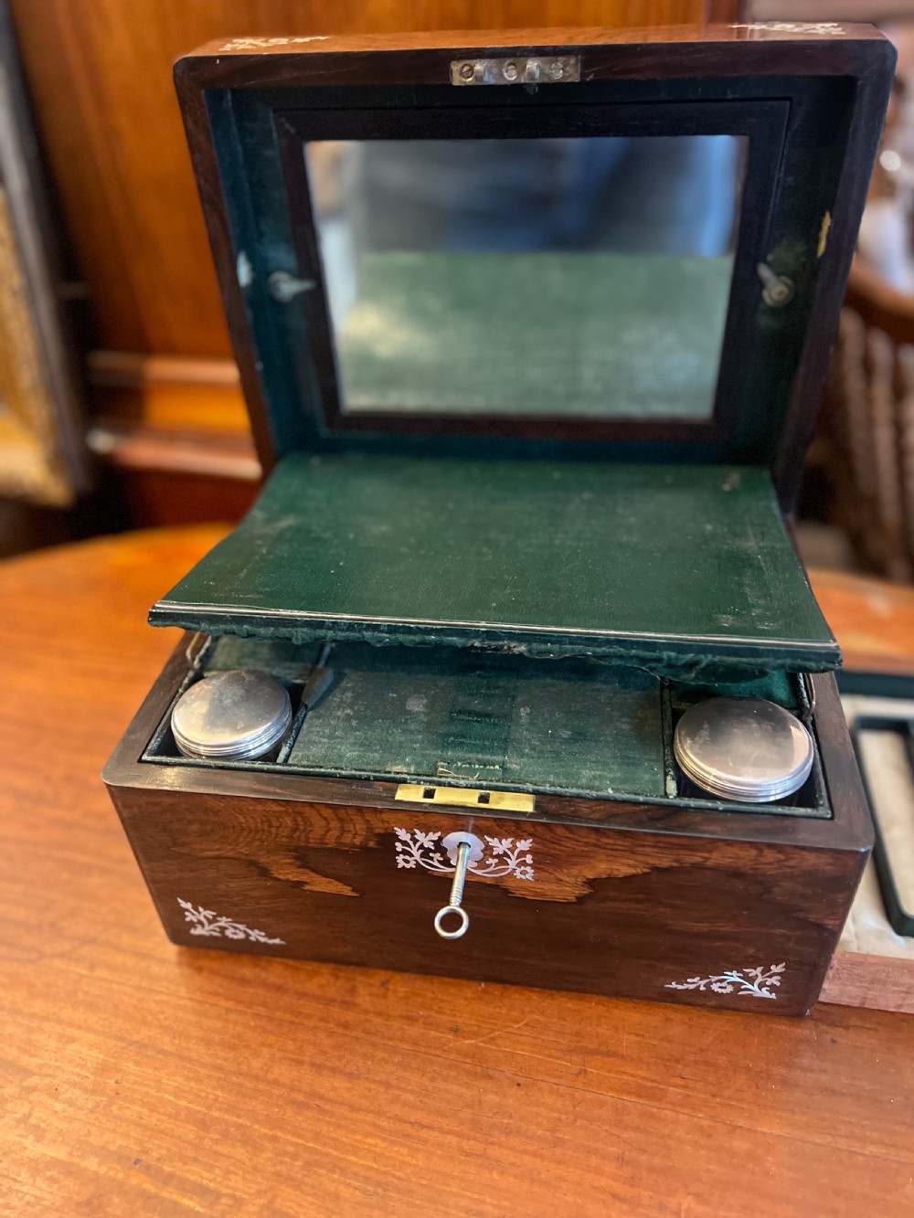 An open Victorian rosewood workbox featuring floral mother of pearl inlay, fitted green velvet interior, silver-toned vanity jars, glass bottles, and two small keys. View IX