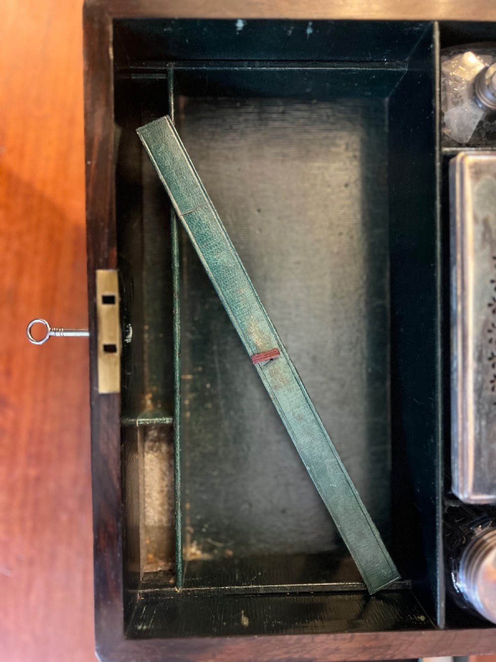 An open Victorian rosewood workbox featuring floral mother of pearl inlay, fitted green velvet interior, silver-toned vanity jars, glass bottles, and two small keys. View XI