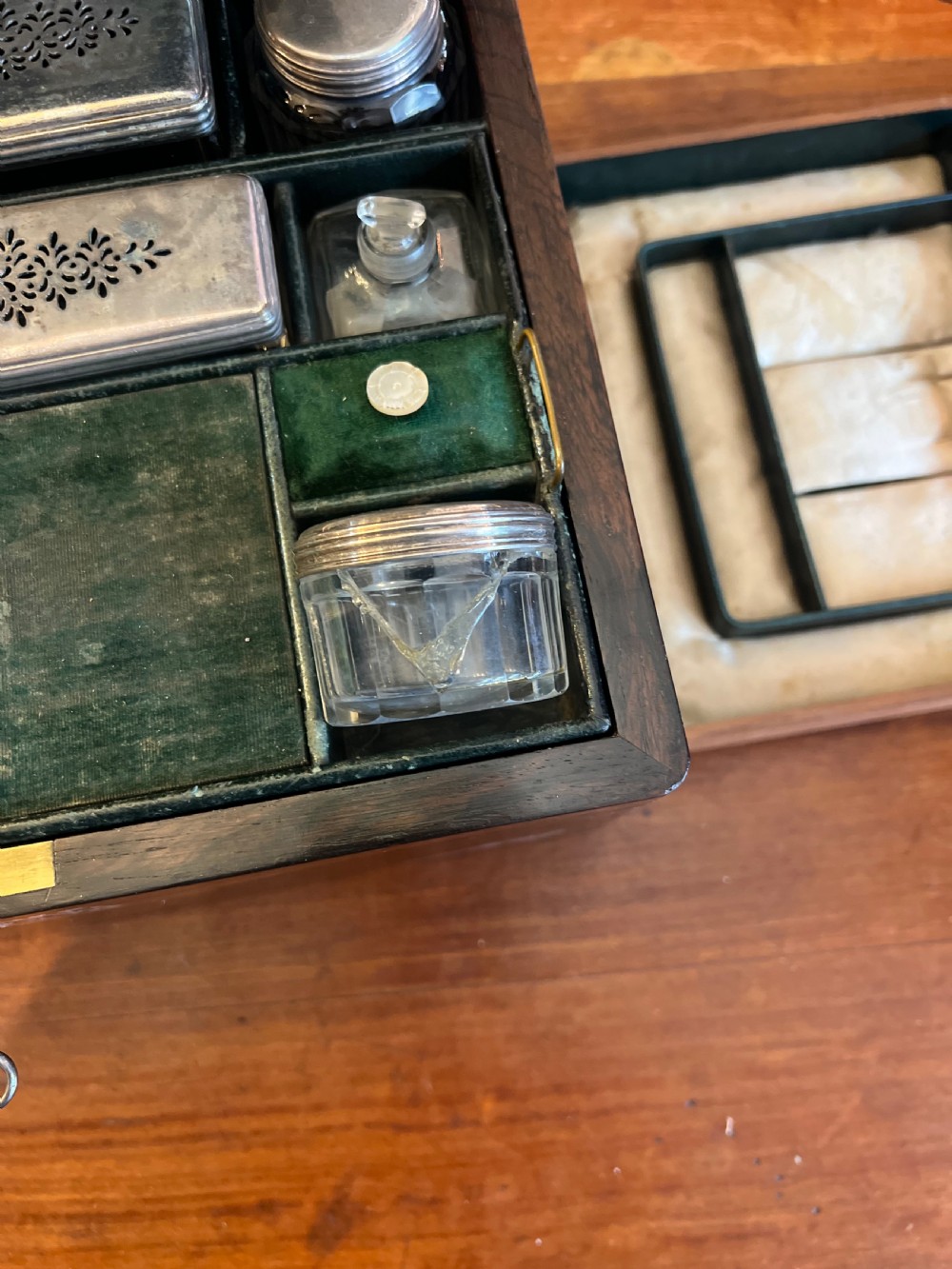 An open Victorian rosewood workbox featuring floral mother of pearl inlay, fitted green velvet interior, silver-toned vanity jars, glass bottles, and two small keys. View XIII