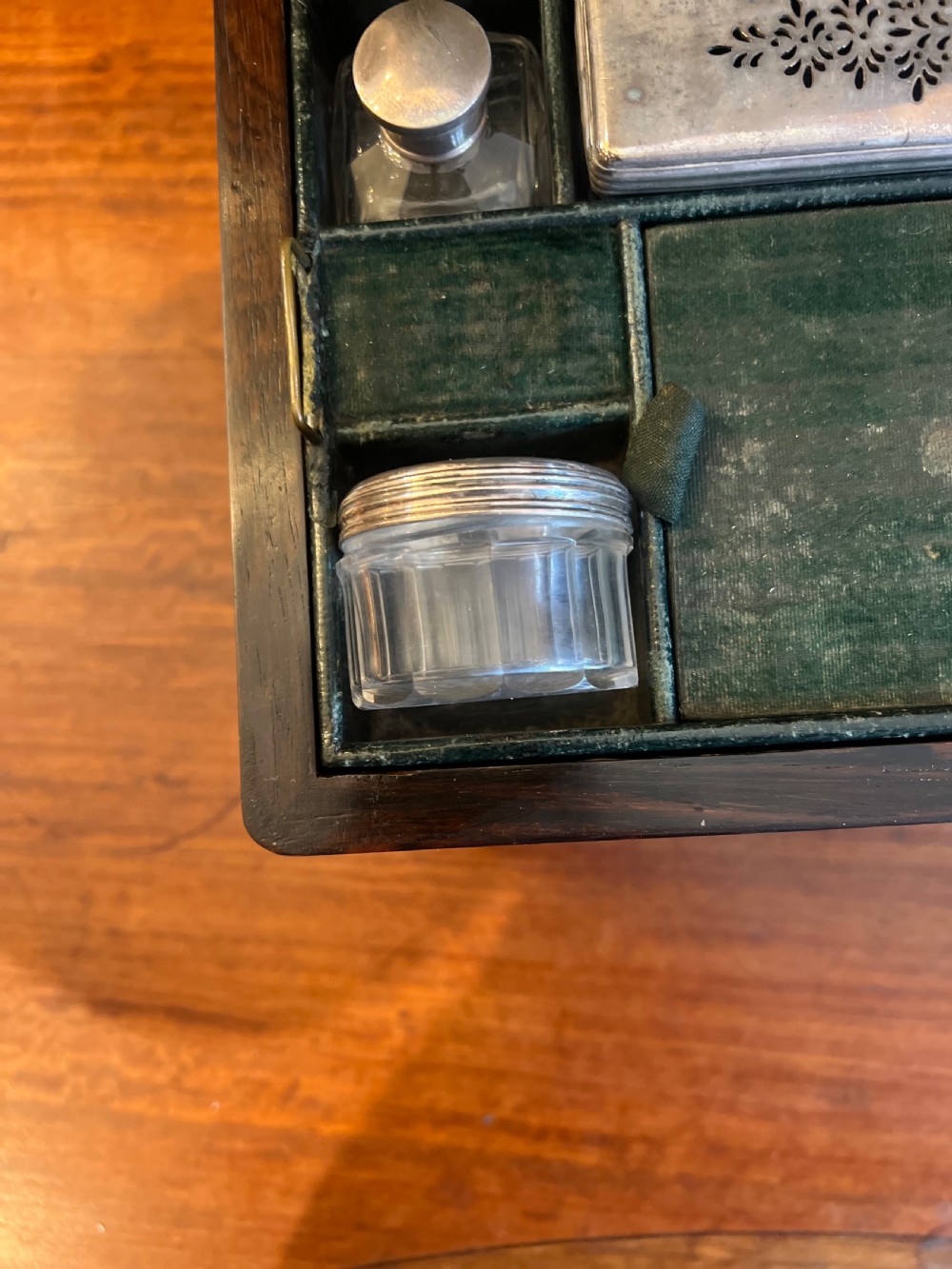 An open Victorian rosewood workbox featuring floral mother of pearl inlay, fitted green velvet interior, silver-toned vanity jars, glass bottles, and two small keys. View XIV