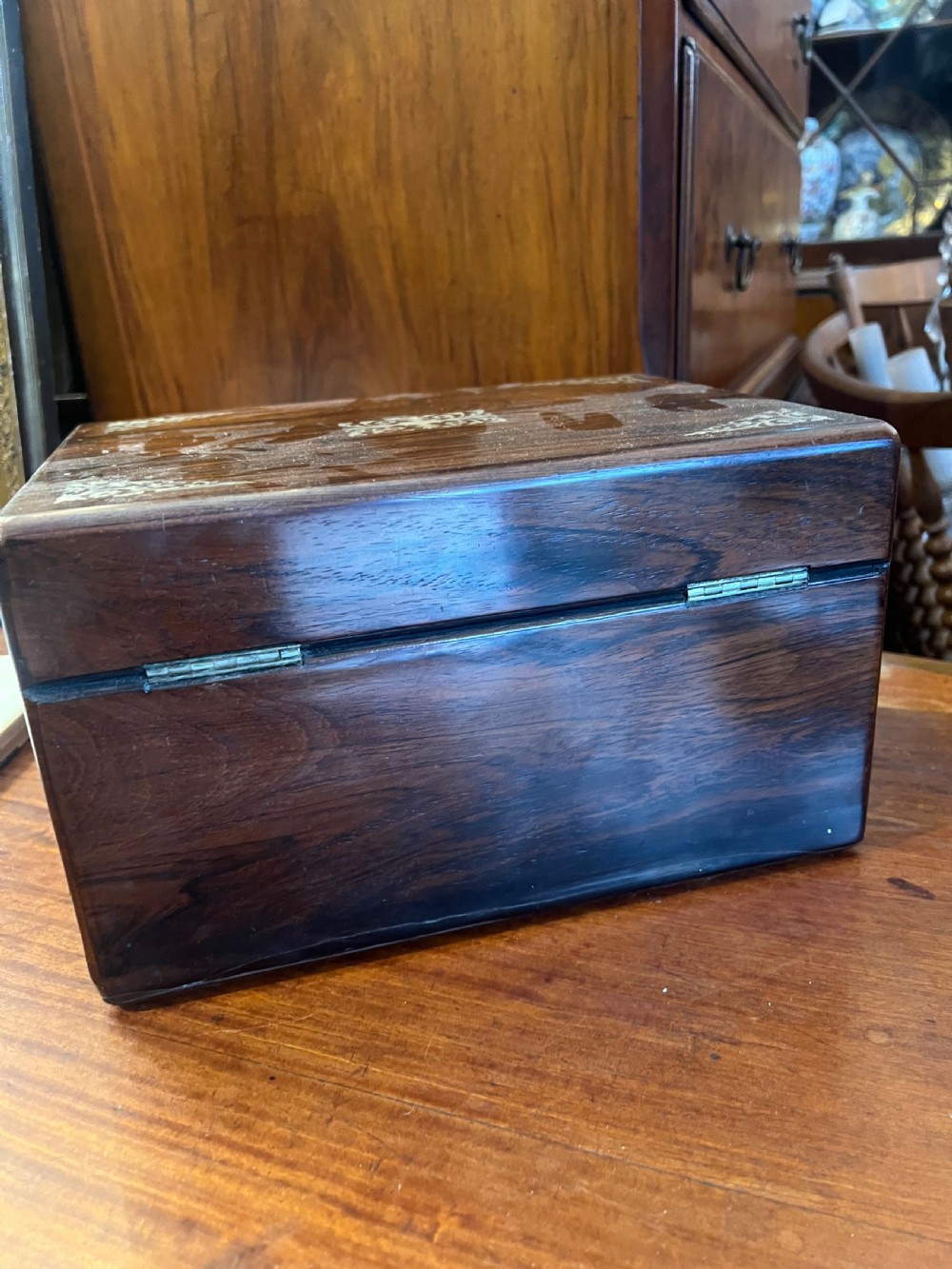 An open Victorian rosewood workbox featuring floral mother of pearl inlay, fitted green velvet interior, silver-toned vanity jars, glass bottles, and two small keys. View XIX