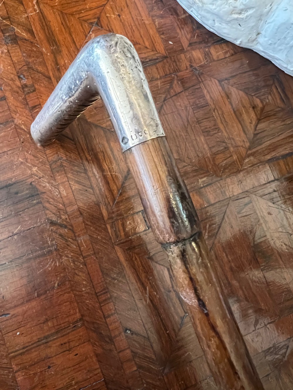 A hallmarked silver L-shaped handle mounted on a linear-grained palm wood walking stick shaft. View III
