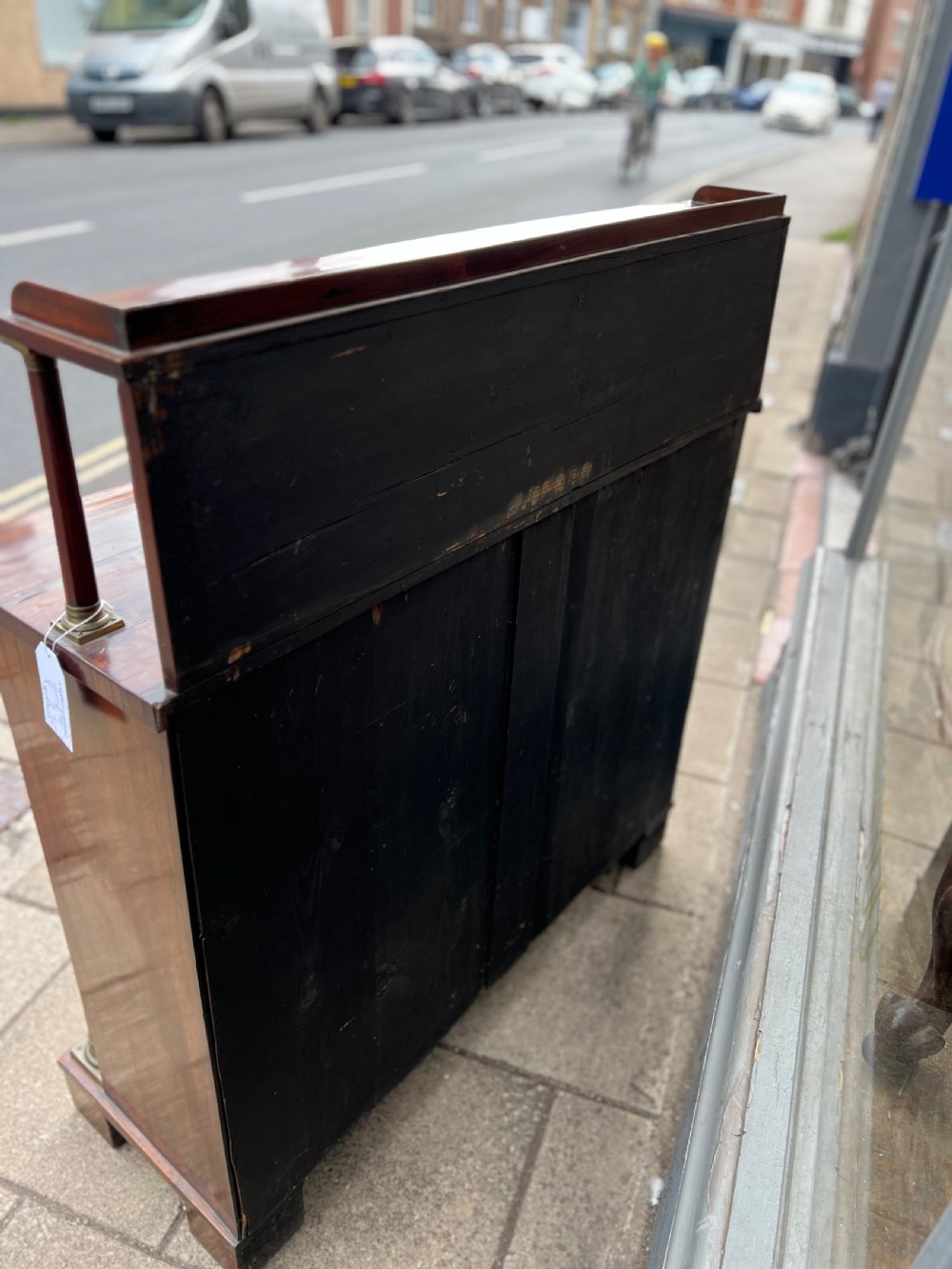 An antique Regency dark rosewood side cabinet featuring brass floral inlay, twin panelled doors, side columns with brass capitals, and an upper shelf resting on turned brass pillars. View XIV