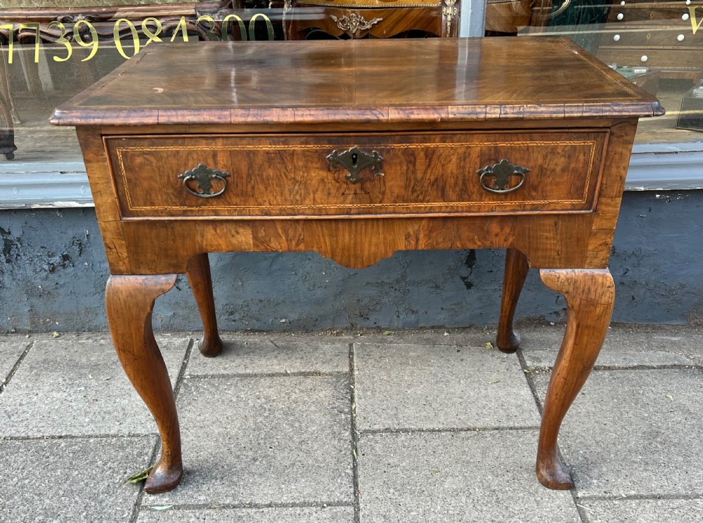 An early Georgian walnut side table with a single drawer, brass handles, shaped apron, and four cabriole legs. View II