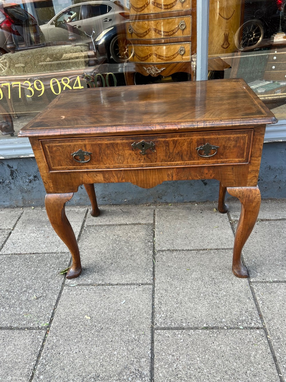 An early Georgian walnut side table with a single drawer, brass handles, shaped apron, and four cabriole legs. View III
