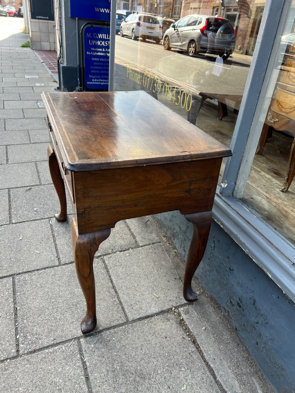 An early Georgian walnut side table with a single drawer, brass handles, shaped apron, and four cabriole legs. View V
