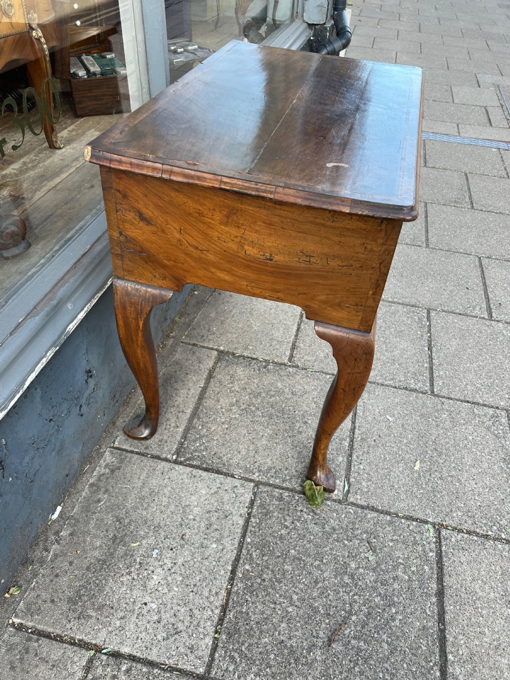 An early Georgian walnut side table with a single drawer, brass handles, shaped apron, and four cabriole legs. View VI