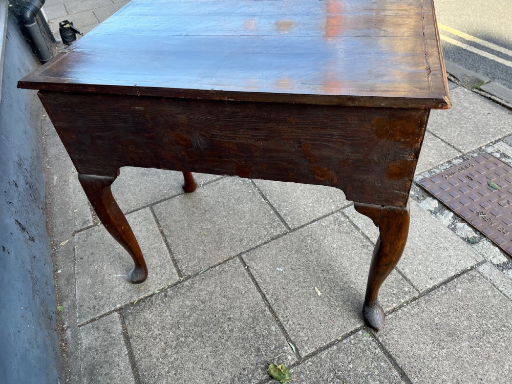 An early Georgian walnut side table with a single drawer, brass handles, shaped apron, and four cabriole legs. View X