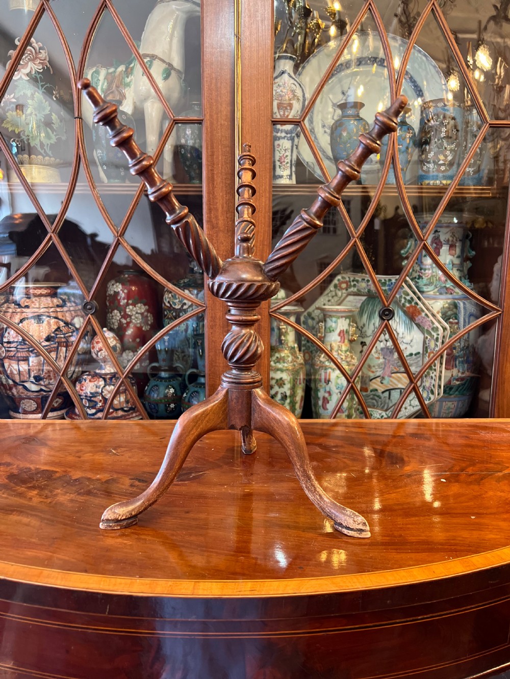 An early nineteenth-century turned wood treen plate stand featuring three spiral-carved upper arms above a turned central column and tripod base.