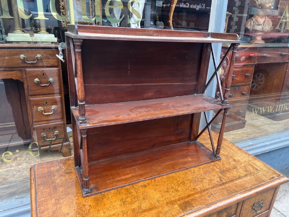 A three-tier Georgian mahogany wall shelf featuring turned spindle supports and open X-frame sides.