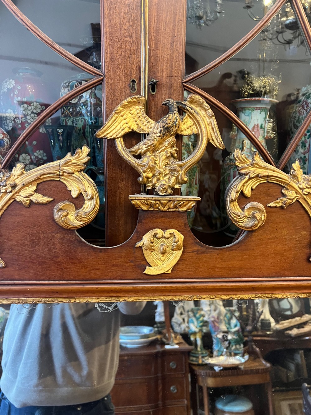 An Edwardian mahogany fretwork wall mirror featuring an ornate parcel gilt eagle finial and classical mask motif. View IV