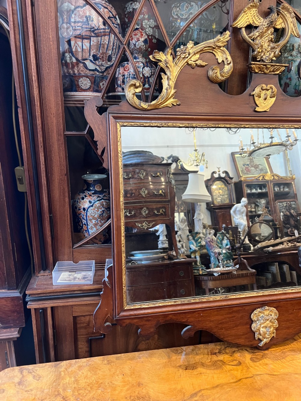 An Edwardian mahogany fretwork wall mirror featuring an ornate parcel gilt eagle finial and classical mask motif. View VII