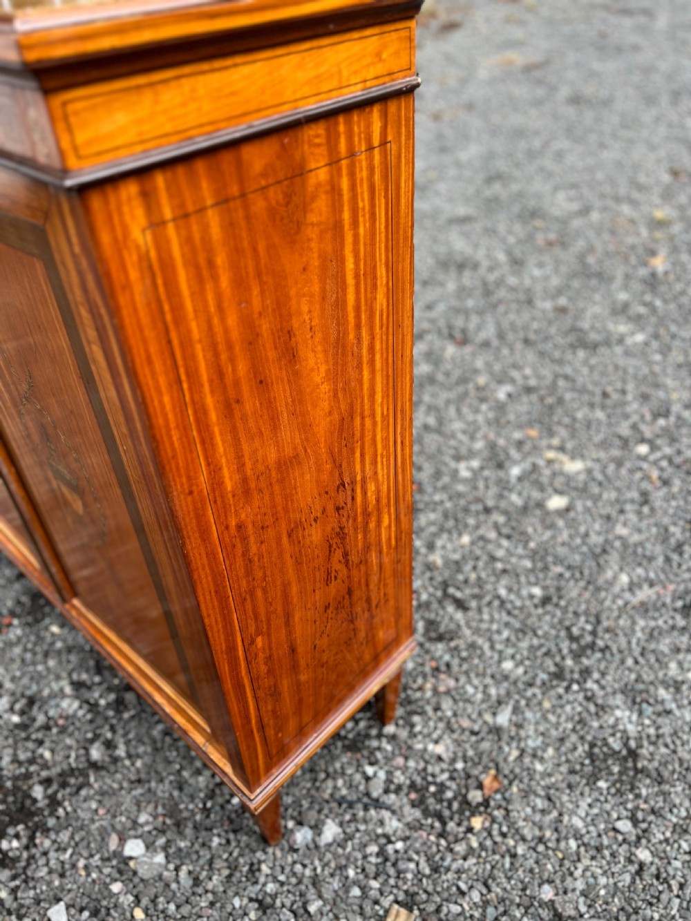 A satinwood side cabinet featuring two cupboard doors with central marquetry urn inlays, a decorated top frieze, and square tapered feet. View IV