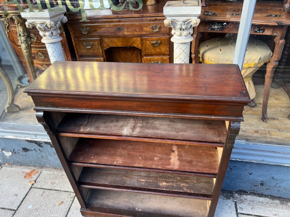 An Edwardian open walnut bookcase featuring four adjustable wooden shelves, side corbel carvings, and a solid plinth base. View II