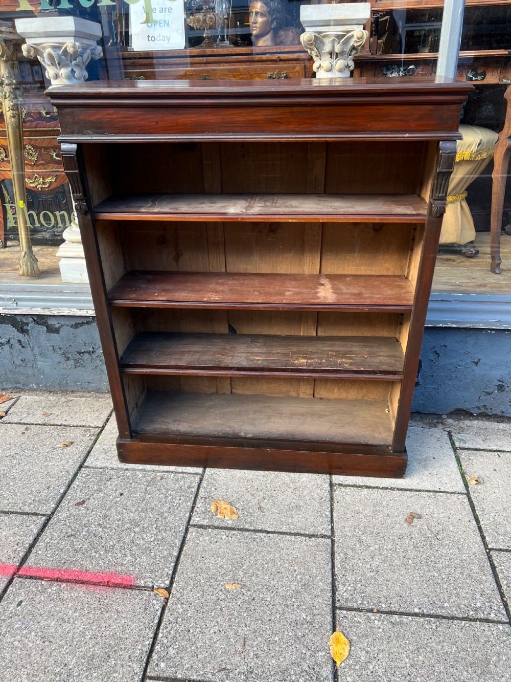 An Edwardian open walnut bookcase featuring four adjustable wooden shelves, side corbel carvings, and a solid plinth base. View III