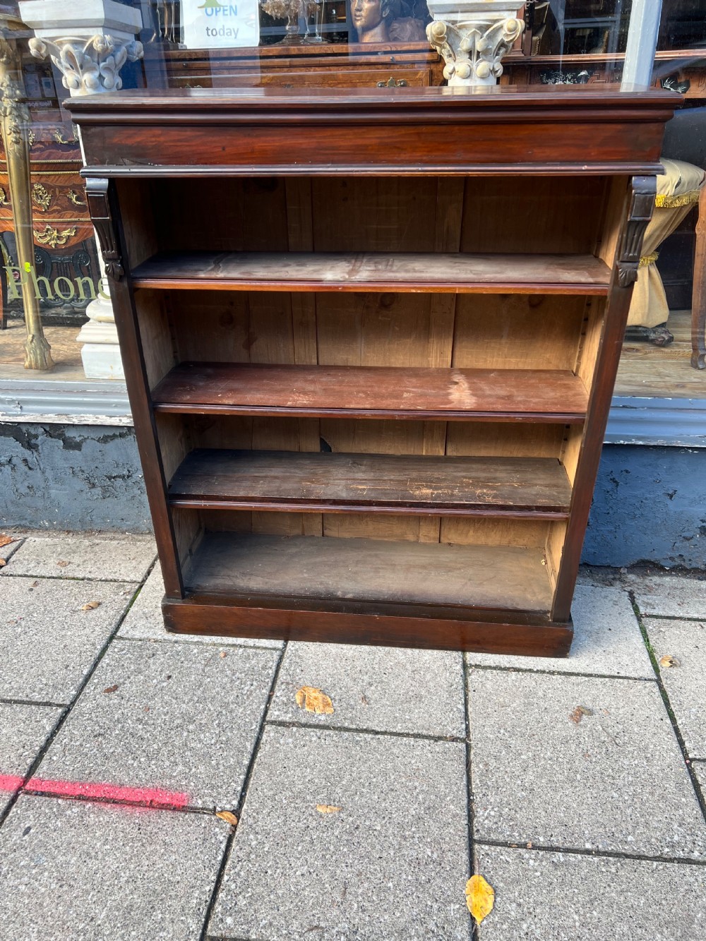 An Edwardian open walnut bookcase featuring four adjustable wooden shelves, side corbel carvings, and a solid plinth base. View IV