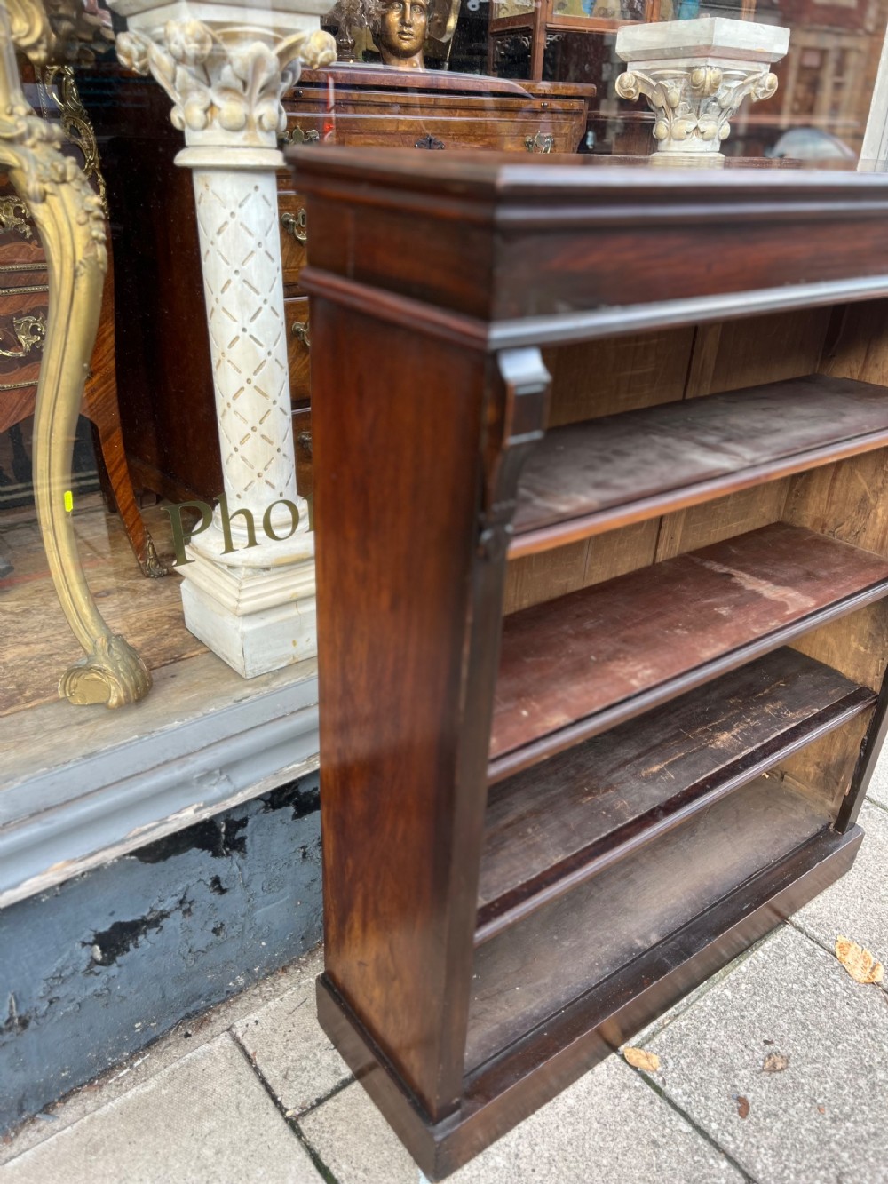 An Edwardian open walnut bookcase featuring four adjustable wooden shelves, side corbel carvings, and a solid plinth base. View XI