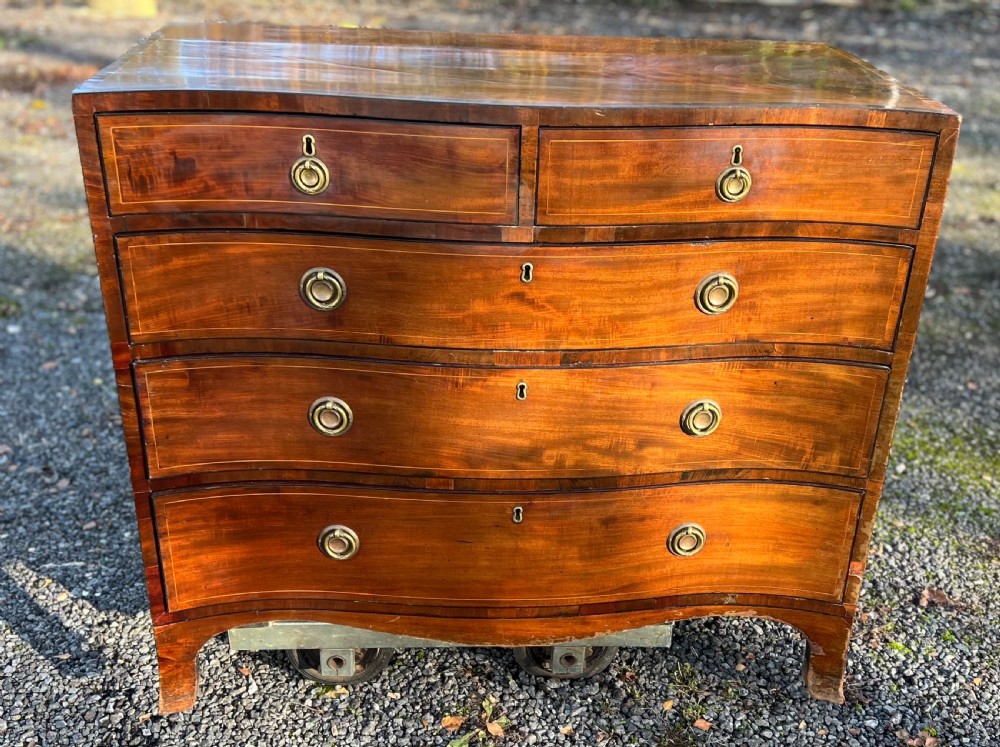 A George III mahogany chest of drawers featuring a serpentine front, line inlay, two short over three long drawers, and brass ring handles. View III