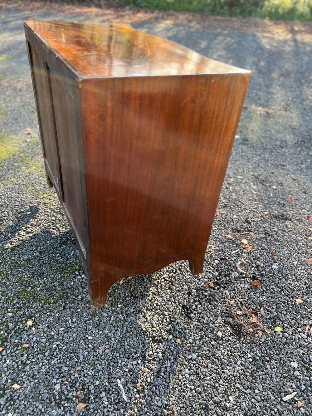A George III mahogany chest of drawers featuring a serpentine front, line inlay, two short over three long drawers, and brass ring handles. View V