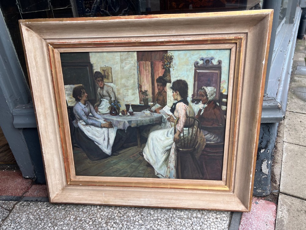 A framed oil on board painting depicting a group of people gathered indoors around a table in a domestic interior scene. View II