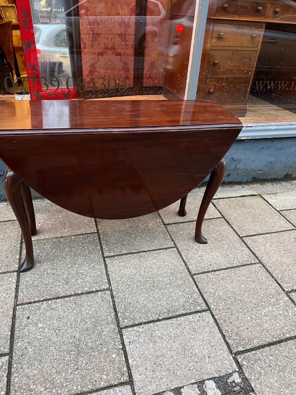 An 18th-century Cuban mahogany drop leaf table with curved cabriole legs and carved pointed pad feet. View II
