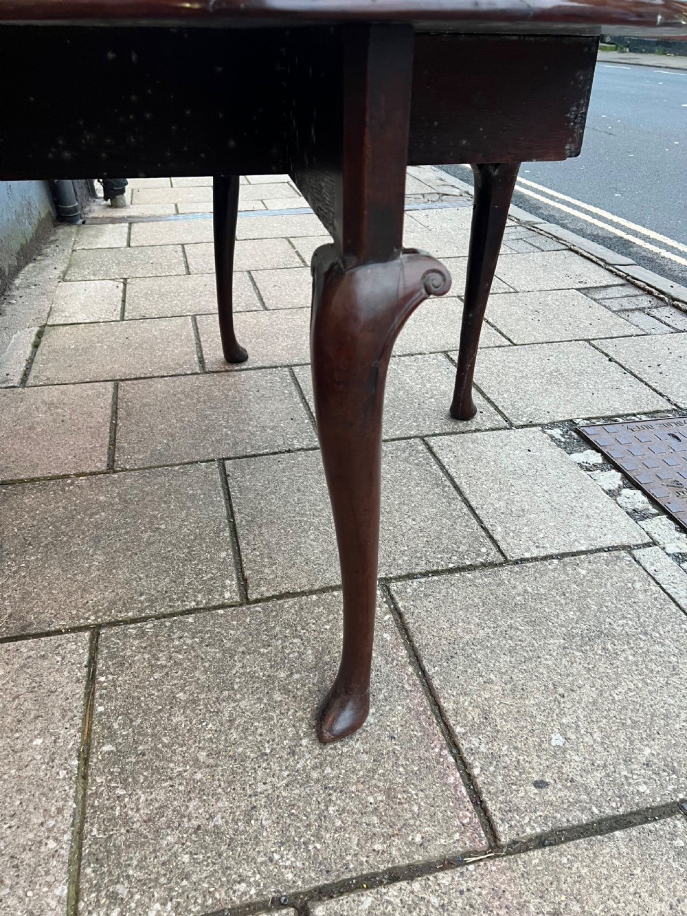An 18th-century Cuban mahogany drop leaf table with curved cabriole legs and carved pointed pad feet. View X